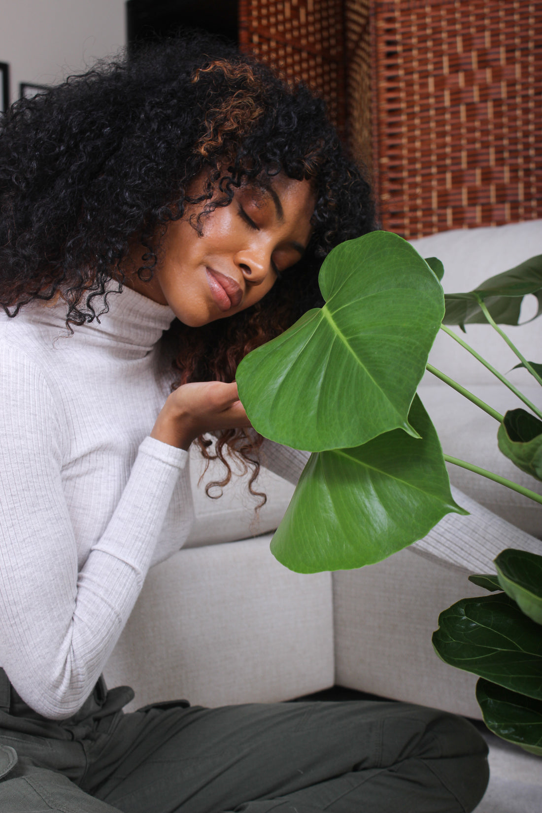 A woman is connecting to her houseplant with a smile on her face.