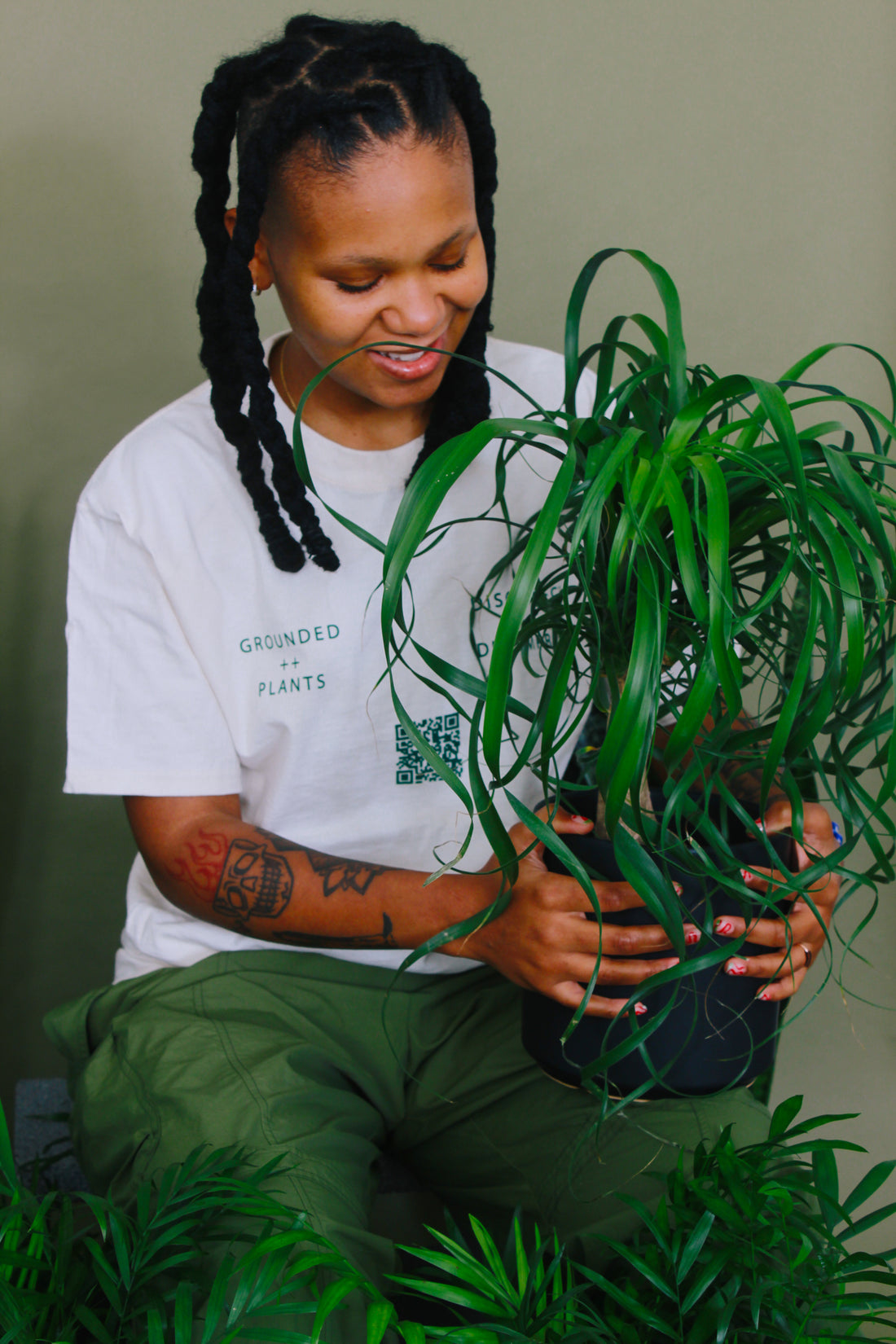 A person is smiling after caring for their ponytail palm plant.