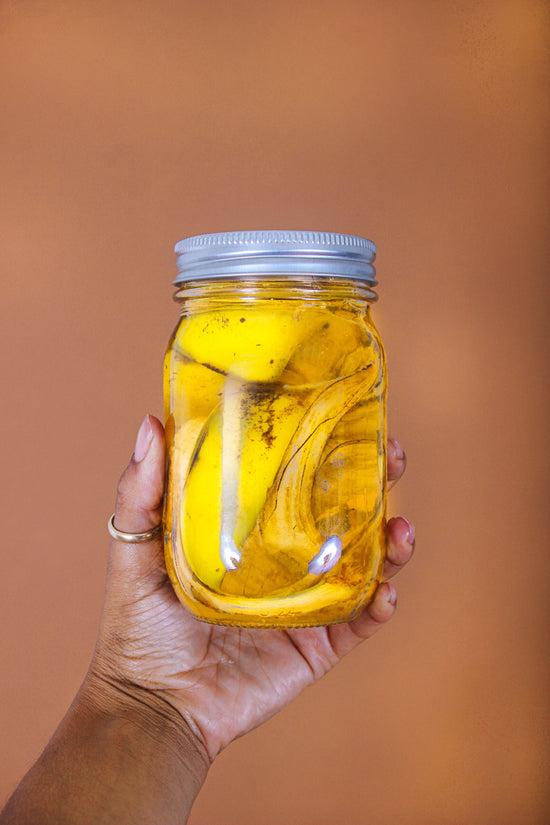 A person holds a mason jar of homeade "banana water" plant fertilizer.