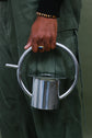 A silver watering can is held in a person&
